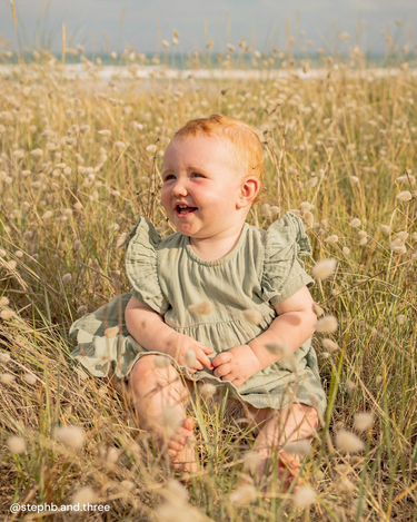 Toddler outside wearing organic cotton muslin short sleeve dress for girls in Matcha sage green – GOTS certified double gauze – embroidered scallop and ruffle detail – Babu