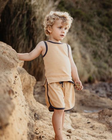 Toddler playing outdoors in organic cotton contrast trim shorts in marigold yellow – GOTS certified – Babu