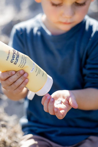 Child holding a tube of sunscreen in a natural setting